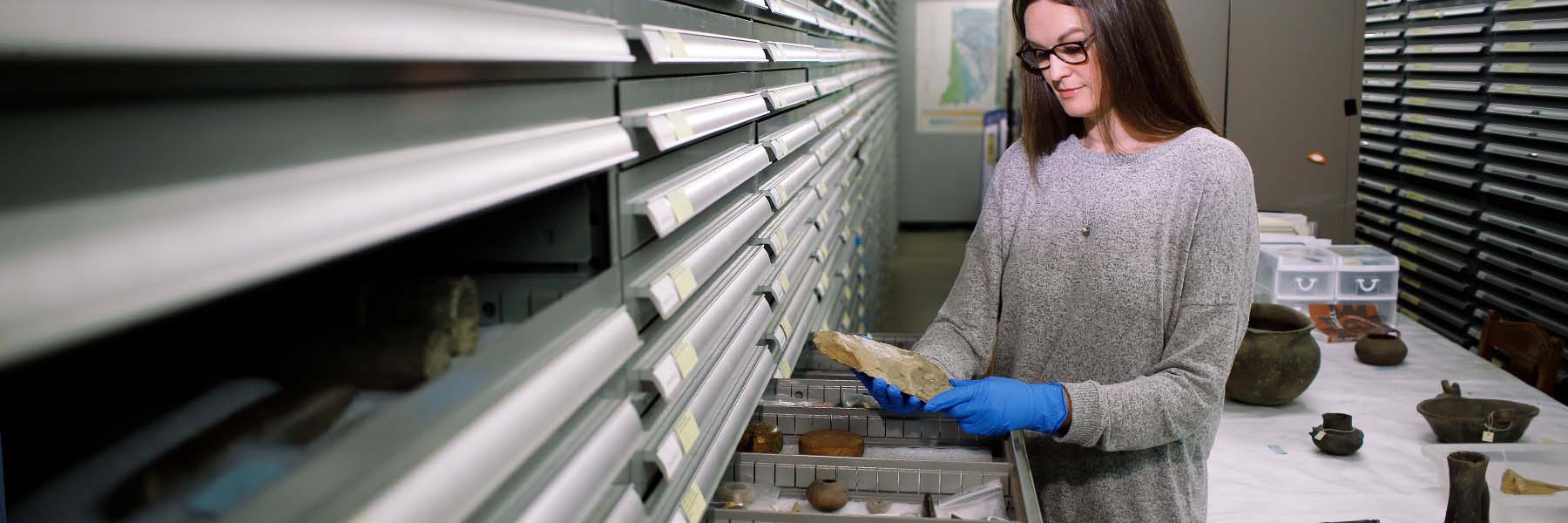A student wearing blue latex gloves holds a rare artifact in her hands.